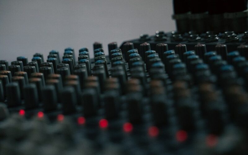 Close-up of a dark audio mixing console with glowing red controls